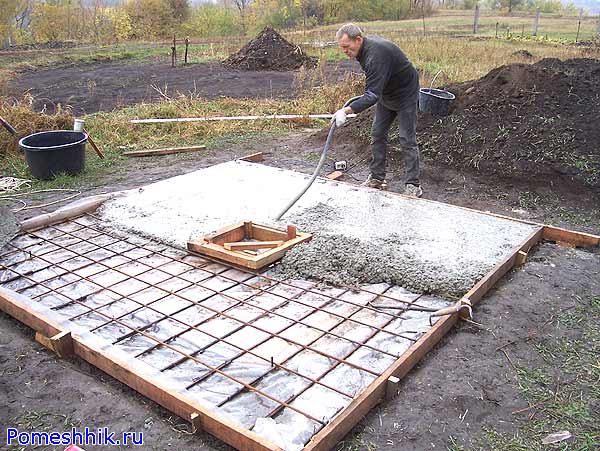 Работник уплотняет вибратором бетон в крышке выгребной ямы
