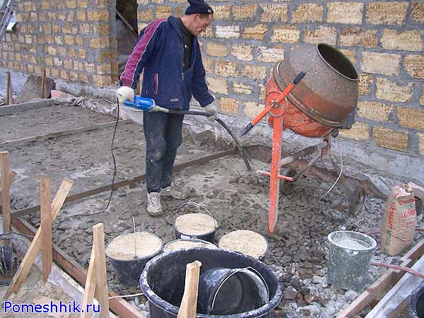 Работник уплотняет вибратором бетон на террасе