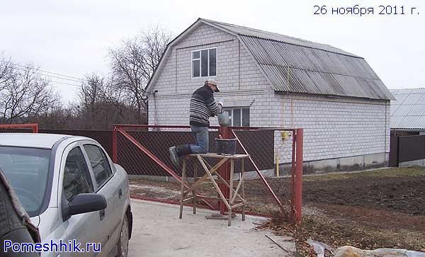 Работник заливает бетоном трубы-столбики ворот