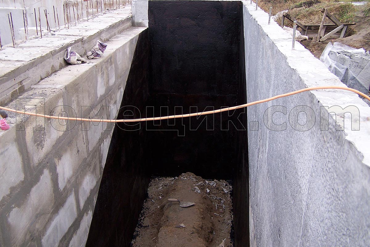 Работник покрыл двумя слоями битумного праймера часть стен входа в подвал, которые будут заплавляться еврорубероидом