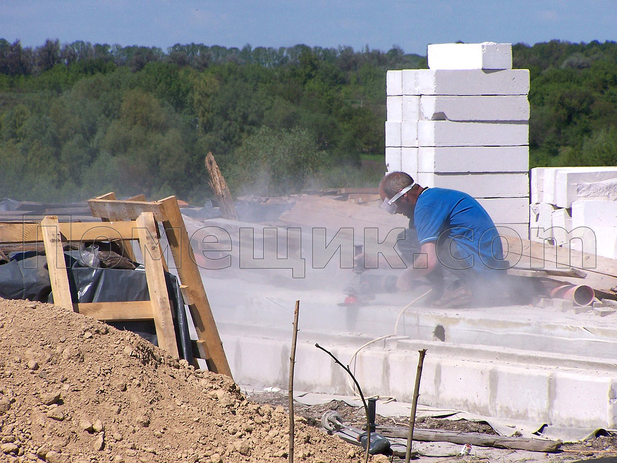 Работник зачищает поверхность на бетонной плите
