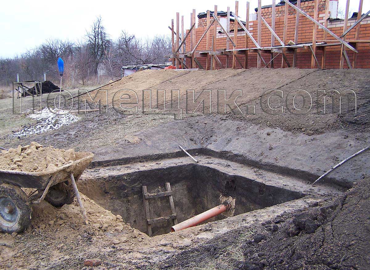 Землю из ямы работник подсыпает под фундамент